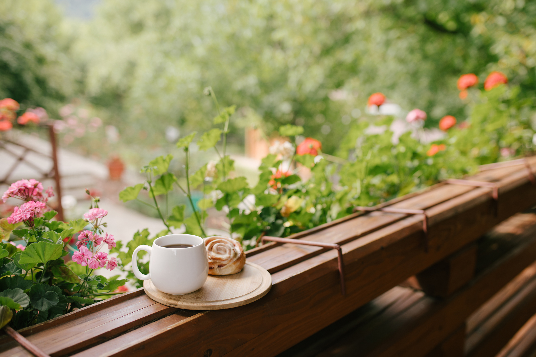 White mug with tea and cinnabon on tray on cozy balcony of wooden cottage.